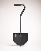 Black overland shovel with a pointed blade, bent handle and rubber grip, on a white background