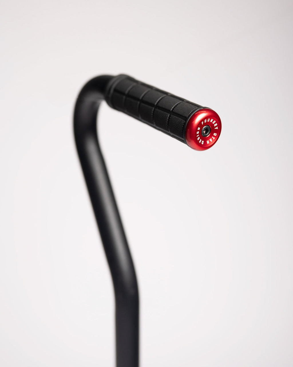 Close-up of the shovel's bent handle with a black rubber grip and red end cap