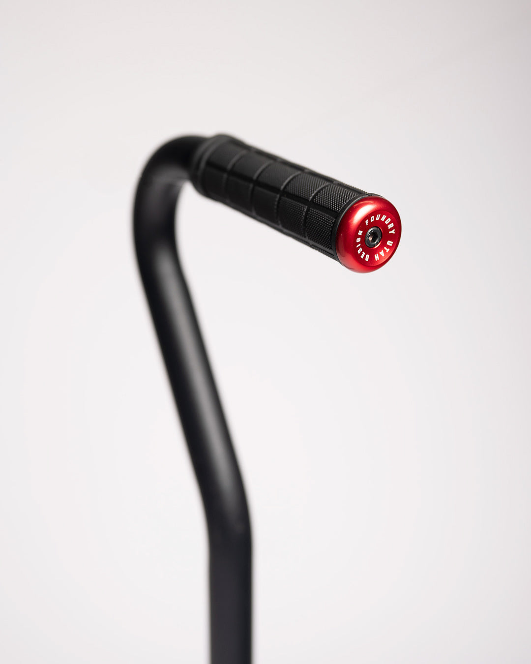 Close-up of the shovel's bent handle with a black rubber grip and red end cap