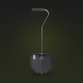Black overland shovel with a pointed blade, bent handle and rubber grip, on a dark olive background