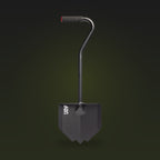 Black overland shovel with a pointed blade, bent handle and rubber grip, on a dark olive background